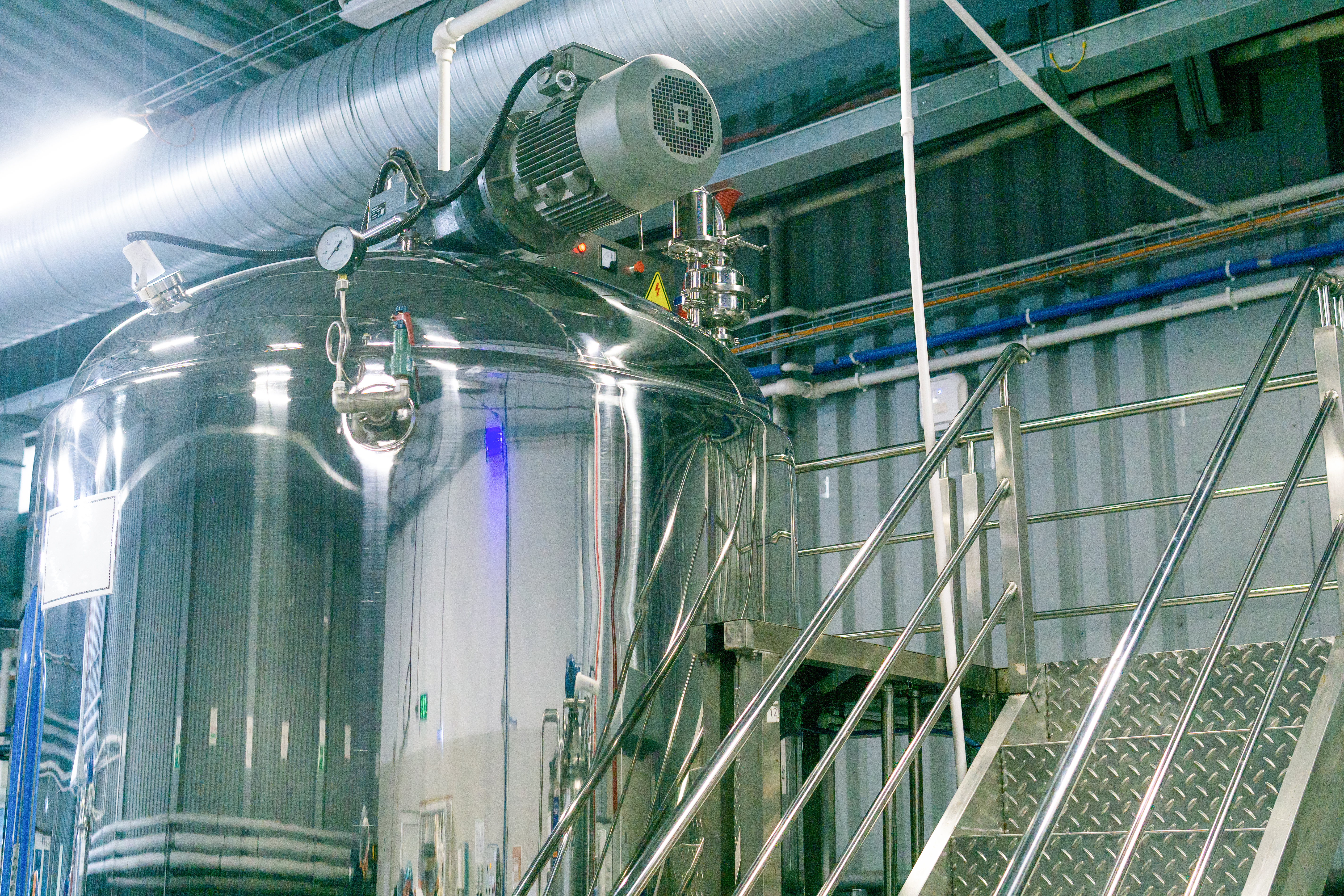 Stainless steel mixing tank with top-entry agitator and motor-driven mixing system.